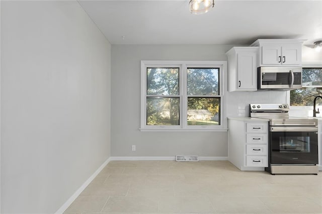 kitchen featuring decorative backsplash, white cabinetry, and stainless steel appliances