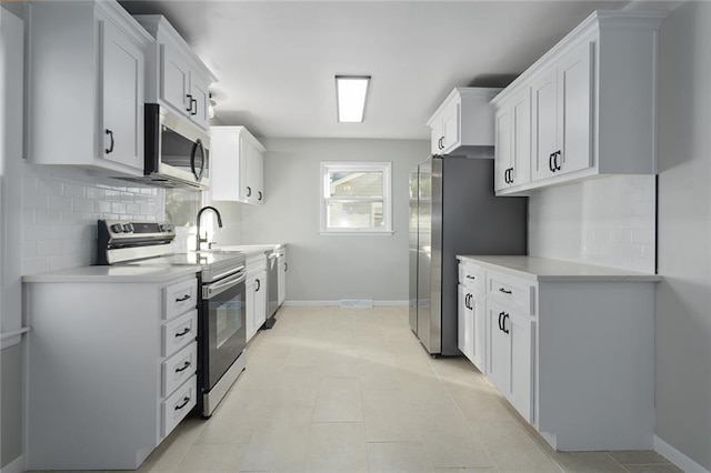 kitchen featuring tasteful backsplash, white cabinetry, light tile patterned floors, and appliances with stainless steel finishes