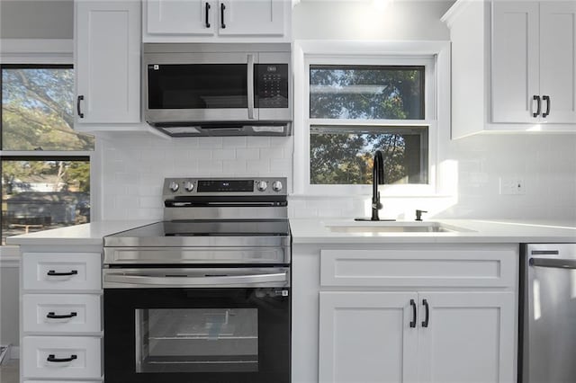 kitchen with white cabinets, appliances with stainless steel finishes, backsplash, and sink