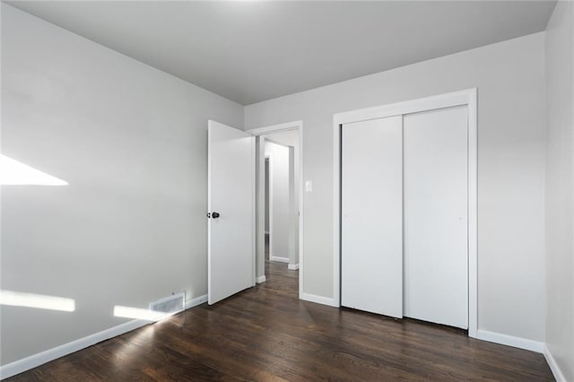 unfurnished bedroom with a closet and dark wood-type flooring