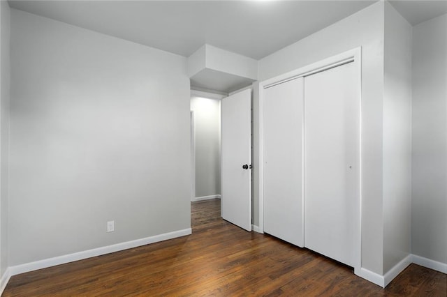 unfurnished bedroom with a closet and dark wood-type flooring