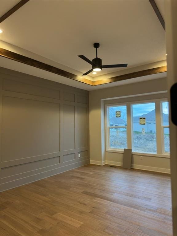 empty room featuring light hardwood / wood-style floors, a raised ceiling, and ceiling fan