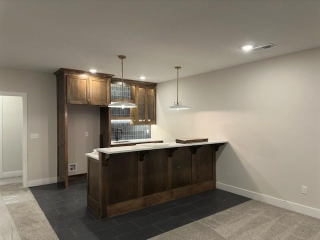 kitchen with a breakfast bar, sink, decorative light fixtures, dark tile patterned flooring, and kitchen peninsula