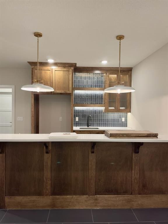 kitchen with hanging light fixtures, sink, dark tile patterned flooring, and decorative backsplash