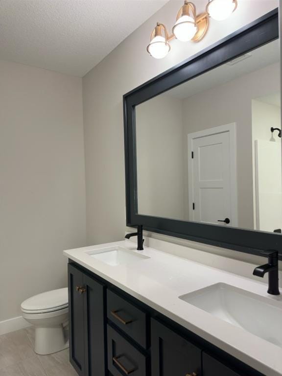 bathroom featuring vanity, toilet, a textured ceiling, and a shower