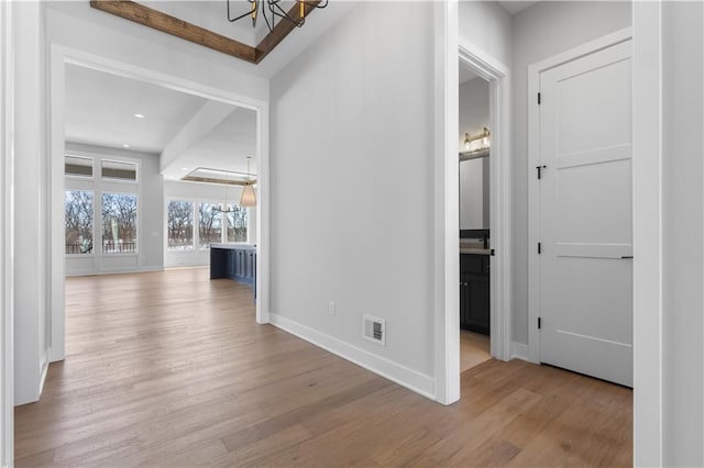 hallway with recessed lighting, visible vents, baseboards, light wood finished floors, and an inviting chandelier