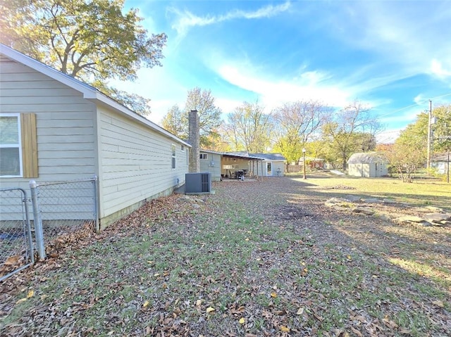 view of yard featuring central AC unit and a storage shed