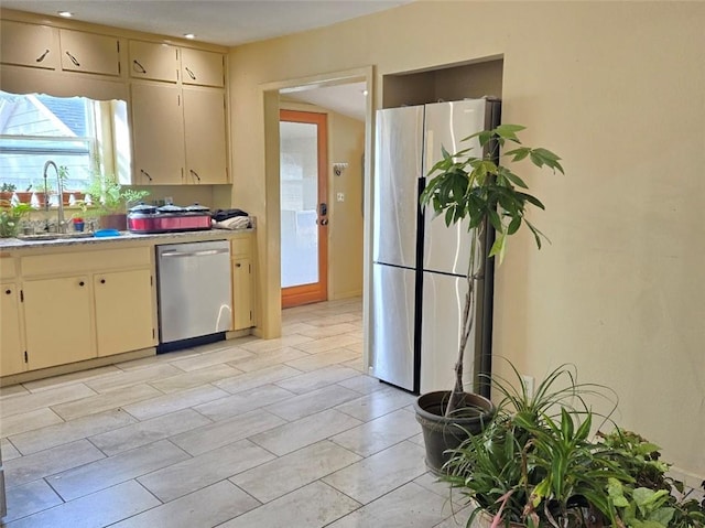 kitchen with appliances with stainless steel finishes, cream cabinets, and sink