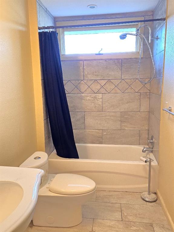 bathroom with tile patterned floors, toilet, and shower / tub combo