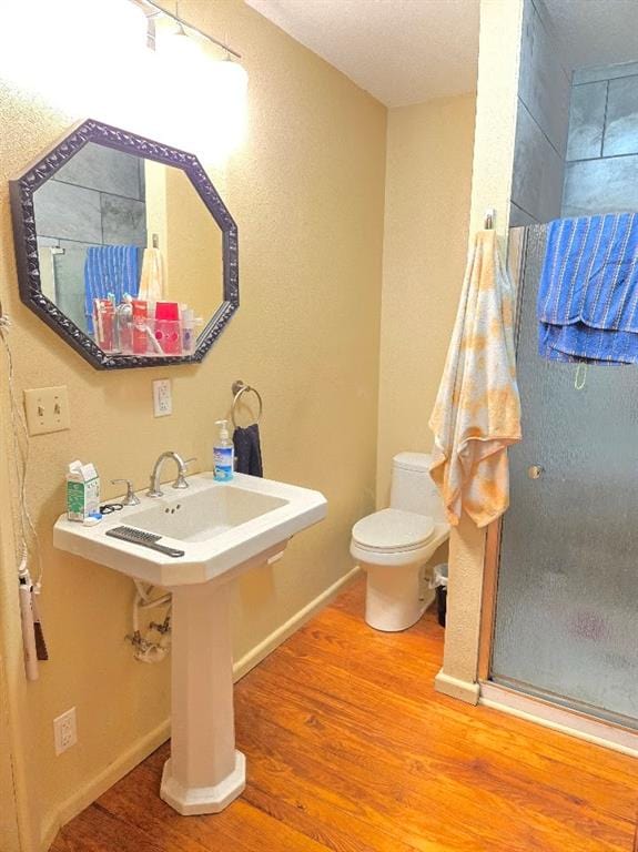 bathroom with a textured ceiling, hardwood / wood-style flooring, and toilet