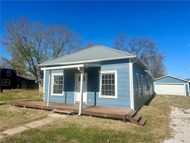 bungalow-style house with a garage, a front lawn, an outdoor structure, and a deck