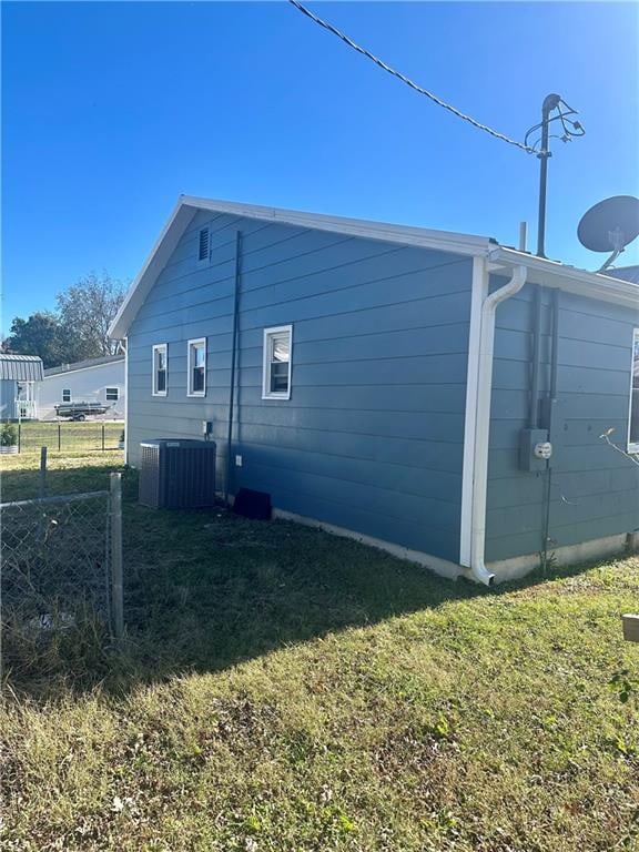 view of side of property with a lawn and cooling unit