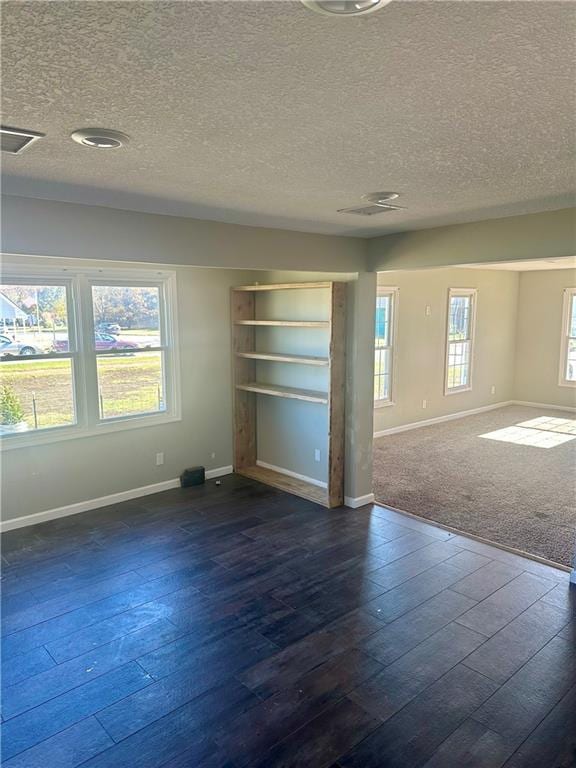 spare room featuring a textured ceiling, plenty of natural light, and dark hardwood / wood-style floors