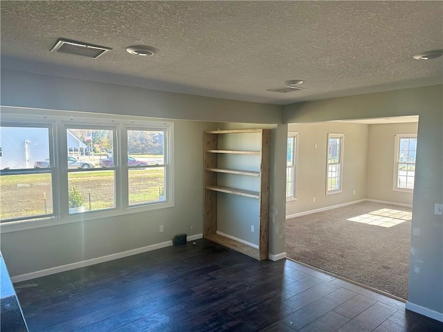 spare room featuring dark wood-type flooring and a textured ceiling