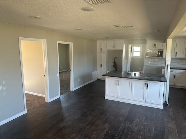 kitchen featuring white cabinets, decorative backsplash, dark hardwood / wood-style flooring, and a textured ceiling