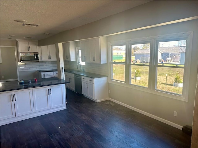 kitchen with white cabinetry, appliances with stainless steel finishes, backsplash, dark hardwood / wood-style floors, and sink