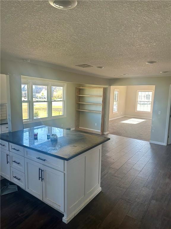 kitchen with dark hardwood / wood-style flooring, white cabinetry, a wealth of natural light, and a textured ceiling