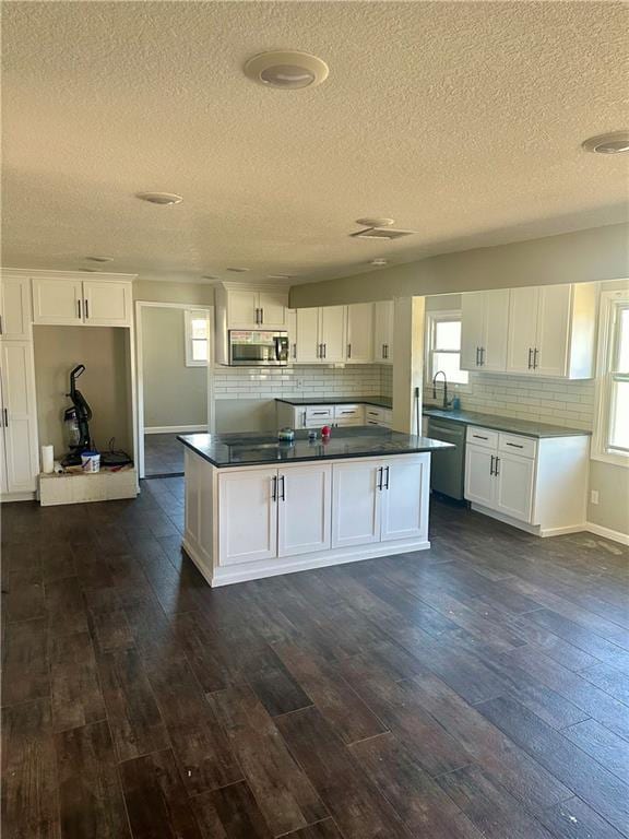 kitchen with dark hardwood / wood-style flooring, white cabinetry, a healthy amount of sunlight, and appliances with stainless steel finishes