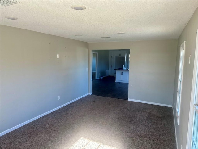 carpeted empty room featuring a textured ceiling