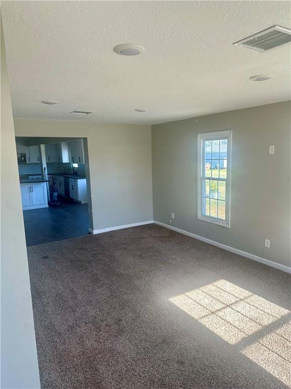 empty room with a textured ceiling and dark colored carpet