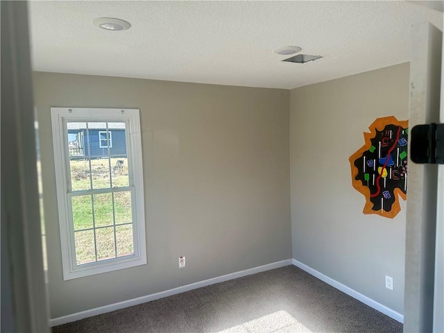 empty room with carpet floors and a textured ceiling