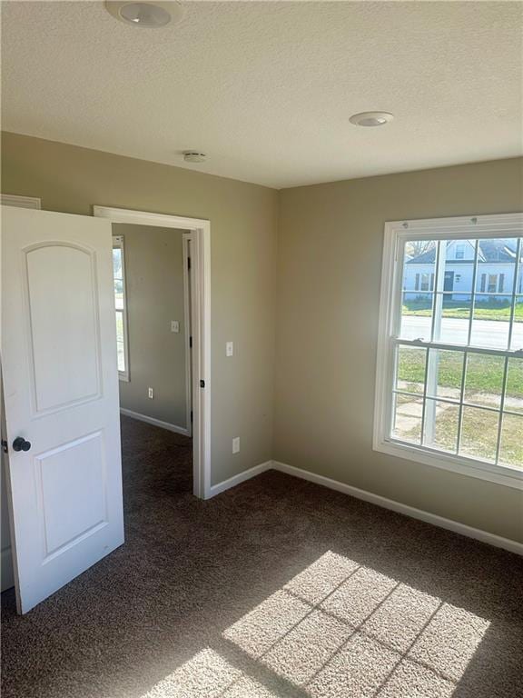 carpeted empty room featuring a textured ceiling