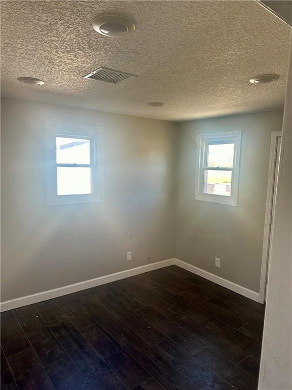 spare room with dark wood-type flooring and a textured ceiling