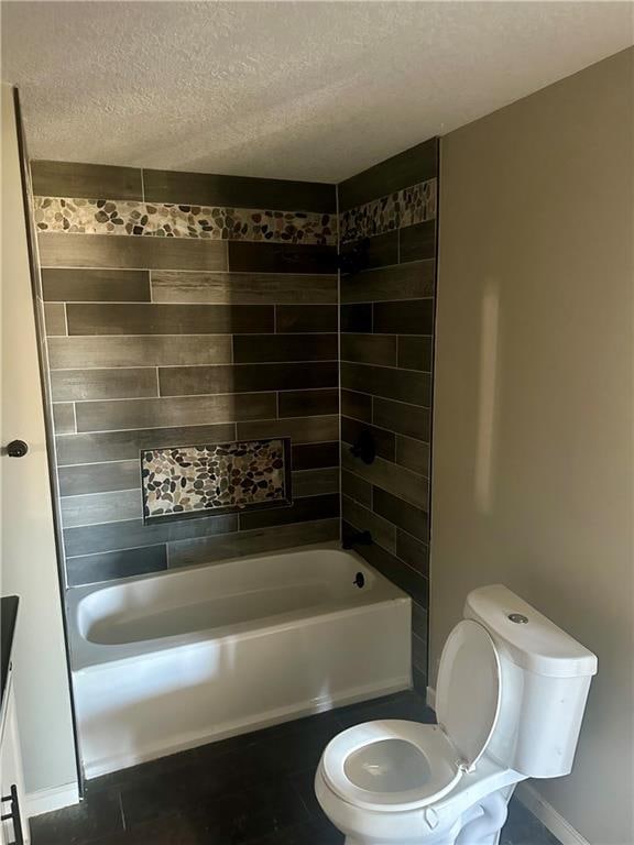 bathroom with toilet, tiled shower / bath combo, a textured ceiling, and tile patterned floors