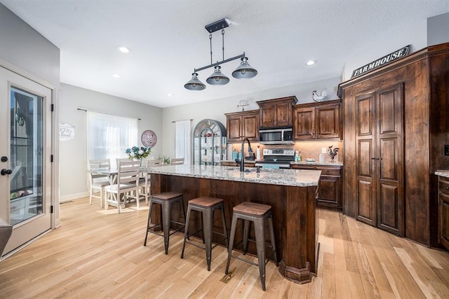 kitchen featuring light hardwood / wood-style flooring, a center island with sink, and stainless steel appliances