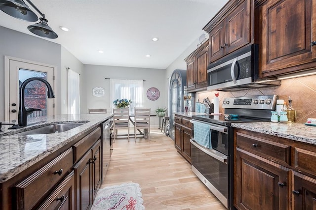 kitchen featuring dark brown cabinets, sink, light wood-type flooring, and appliances with stainless steel finishes