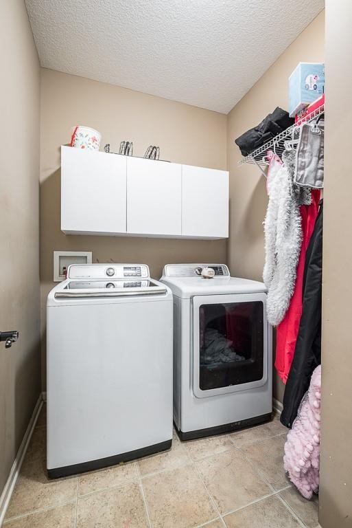 clothes washing area with cabinets, independent washer and dryer, and a textured ceiling