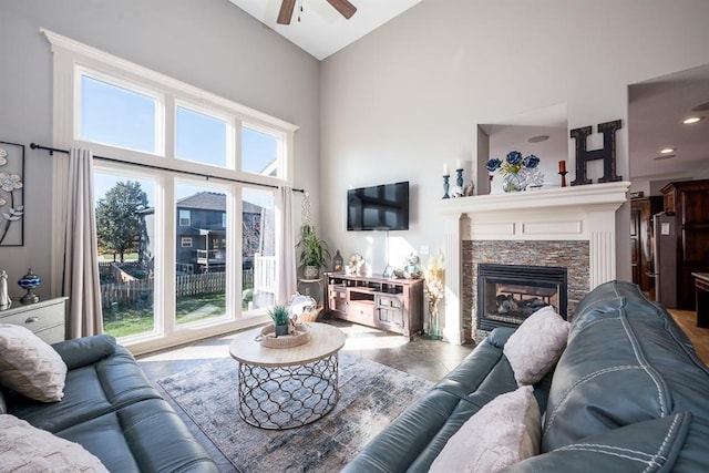 tiled living room with a fireplace, ceiling fan, and high vaulted ceiling