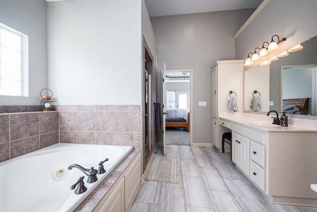 bathroom with vanity, a healthy amount of sunlight, and tiled tub