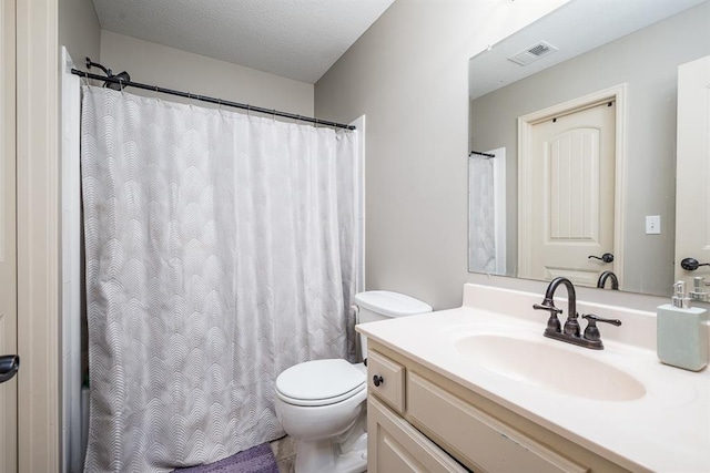 bathroom with vanity, toilet, and a textured ceiling