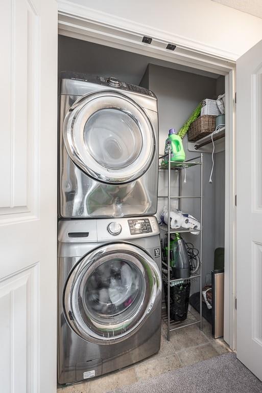 laundry room with stacked washer and clothes dryer and tile patterned flooring