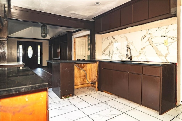 kitchen featuring dark brown cabinets, crown molding, kitchen peninsula, and sink