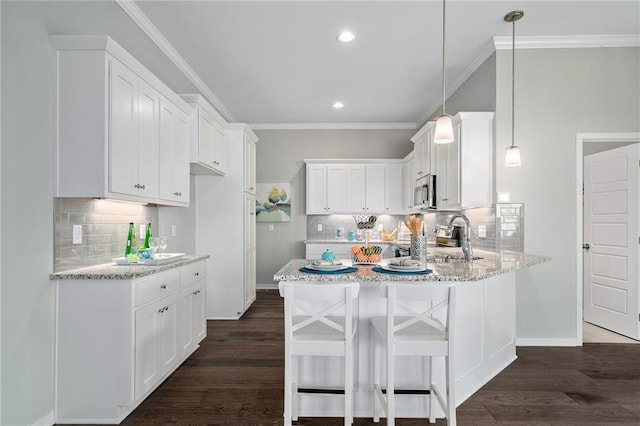 kitchen with white cabinets, a kitchen bar, dark hardwood / wood-style floors, and decorative light fixtures