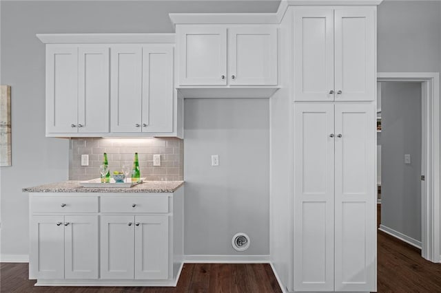 kitchen with white cabinets, light stone countertops, dark hardwood / wood-style floors, and backsplash