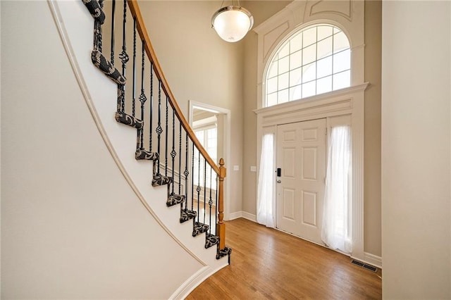 entrance foyer with a wealth of natural light, a towering ceiling, and wood-type flooring