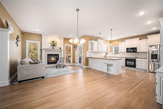 kitchen featuring a breakfast bar, light wood-type flooring, white cabinetry, and black appliances