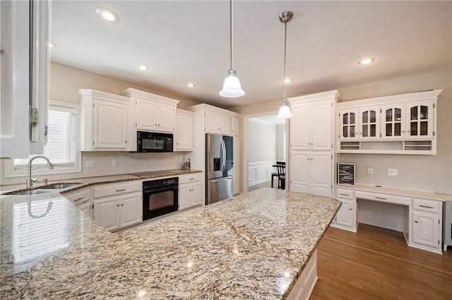 kitchen featuring black appliances, white cabinetry, sink, and hanging light fixtures