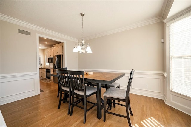 dining space with ornamental molding, a notable chandelier, and light wood-type flooring