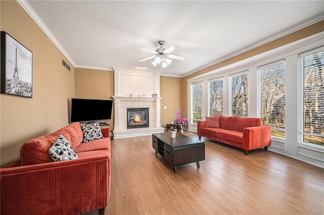 living room featuring a fireplace, hardwood / wood-style floors, a textured ceiling, and ornamental molding