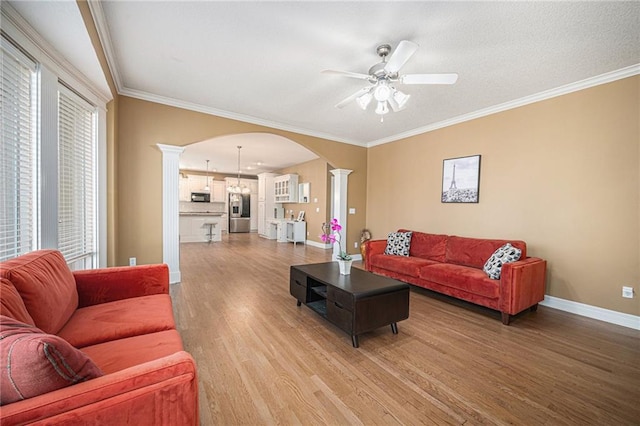 living room featuring decorative columns, crown molding, ceiling fan, and hardwood / wood-style flooring