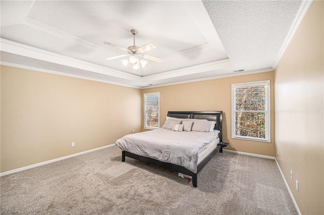 carpeted bedroom featuring a textured ceiling, ceiling fan, crown molding, and a tray ceiling