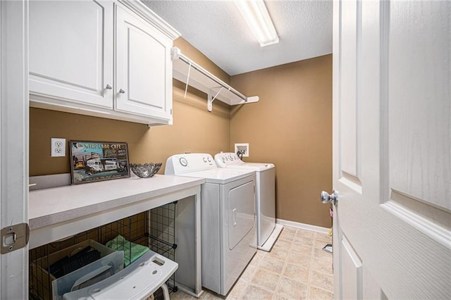 washroom with cabinets, washer and dryer, and a textured ceiling