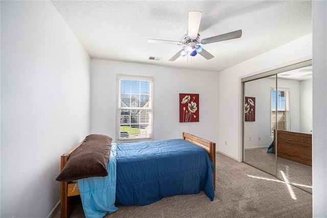 bedroom featuring ceiling fan, a closet, carpet, and a textured ceiling