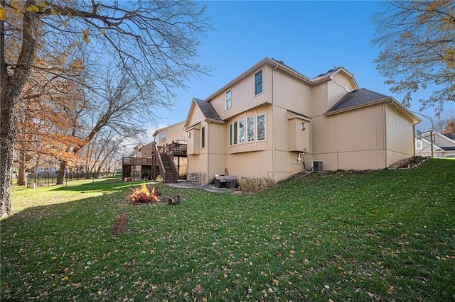 rear view of property with central AC, a wooden deck, and a lawn