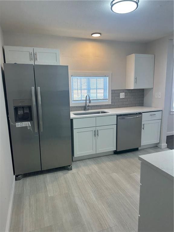 kitchen featuring backsplash, sink, light hardwood / wood-style flooring, appliances with stainless steel finishes, and white cabinetry