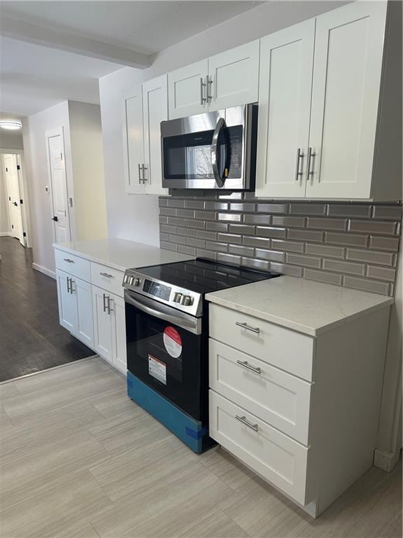 kitchen featuring backsplash, light stone countertops, beamed ceiling, white cabinetry, and stainless steel appliances